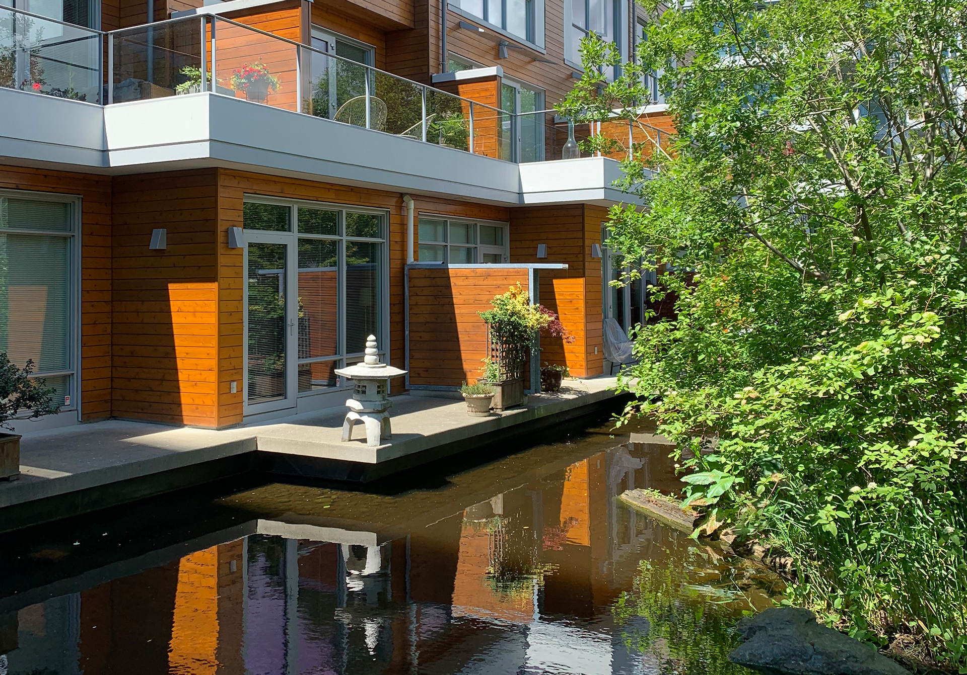 NAM and housing - Dockside Green, Victoria BC - modern wood clad building with lots of greenery and a prominent water feature in the foreground